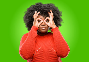 Beautiful african woman looking at camera through her fingers in ok gesture. Imitating binoculars