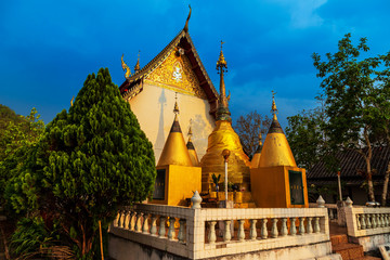 Fototapeta premium Golden light shining on white and gold pagoda during sunrise / sunset with blue sky in Mae hong son Thailand