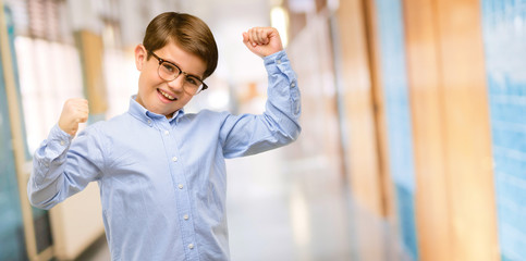 Handsome toddler child with green eyes happy and excited celebrating victory expressing big success, power, energy and positive emotions. Celebrates new job joyful at school corridor