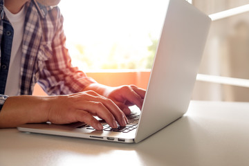 Fototapeta premium Side view shot of a man's hands typing on laptop keyboard for business or education, Online shopping concept.