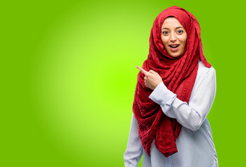 Young arab woman wearing hijab pointing away side with finger