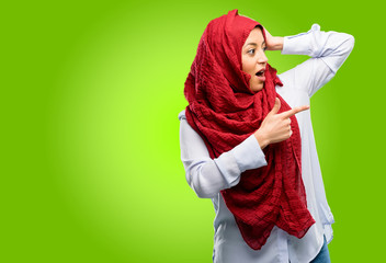 Young arab woman wearing hijab pointing away side with his finger