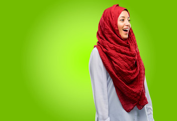 Young arab woman wearing hijab happy and surprised cheering expressing wow gesture