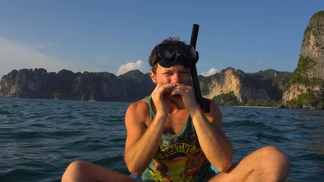 Man Playing Harp on Kayak in the Open Sea Water in Mask and Tube for Diving or Snorkeling. Railey Beach, Krabi, Thailand.