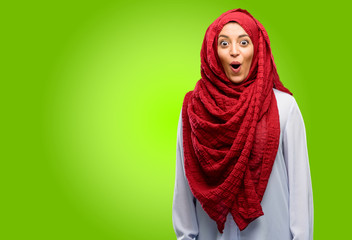 Young arab woman wearing hijab happy and surprised cheering expressing wow gesture