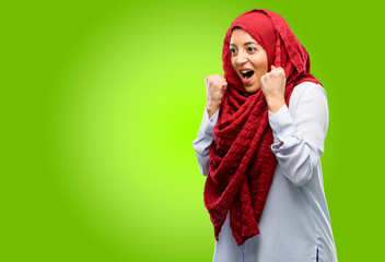 Young arab woman wearing hijab happy and excited expressing winning gesture. Successful and celebrating victory, triumphant