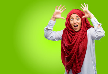 Young arab woman wearing hijab happy and surprised cheering expressing wow gesture