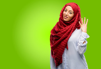 Young arab woman wearing hijab raising his finger, is the number four