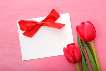 Tulips with greeting card on a pink background