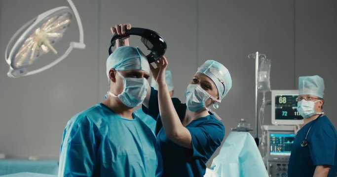 Nurse assisting surgeon with mounting augmented reality holographic hololens glasses before operation. 4K UHD 60 FPS SLO MO