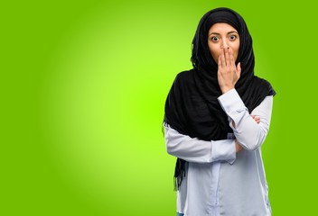 Young arab woman wearing hijab covers mouth in shock, looks shy, expressing silence and mistake concepts, scared