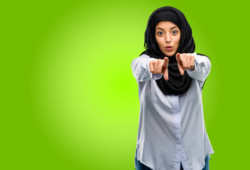 Young arab woman wearing hijab pointing to the front with finger