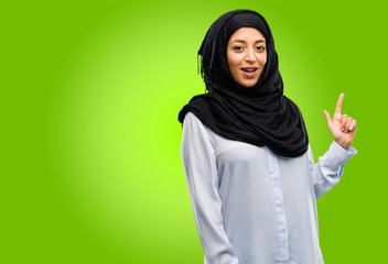 Young arab woman wearing hijab pointing away side with finger