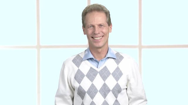 Cheerful male persom on blurred background. Happy mature man wearing sweater and shirt. Positive middle-aged man.