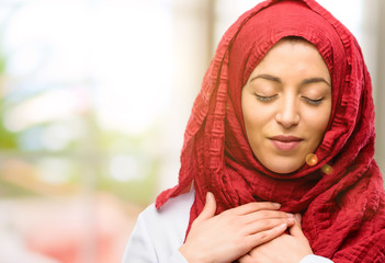Young arab woman wearing hijab with hands in heart, expressing love and health concept
