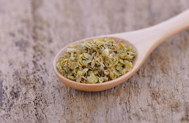 Oregano on wooden spoon isolated on wwooden background.
