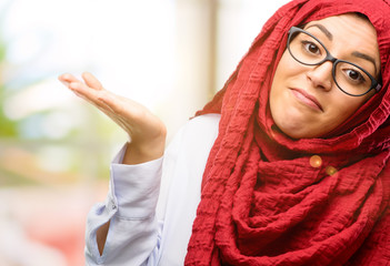 Young arab woman wearing hijab doubt expression, confuse and wonder concept, uncertain future