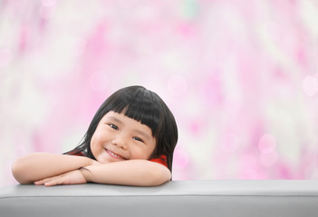 Obraz na płótnie Canvas Asian children cute or kid girl happy fun and smile with wear red shirt on sofa at preschool or nursery and child hospital on pink bokeh background with space