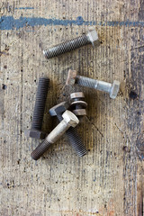 Old, dirty screws against wooden plank.