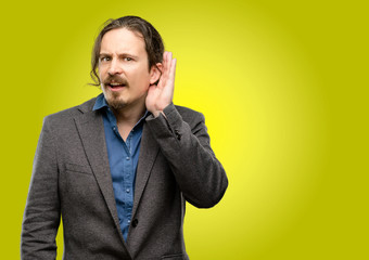 Handsome young man holding hand near ear trying to listen to interesting news expressing communication concept and gossip