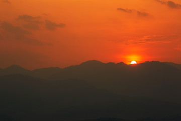 Red and orange warm sunlight in the sky during sunset with mountain  range in foreground, shade and shadow, sunset sunrise
