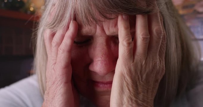 Close-up of stressed senior woman face in pain in domestic home setting, Tight shot of elderly woman with migraine headache in her living room, 4k 