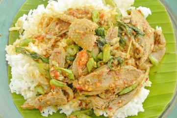 spicy fried duck meat curry with basil leaf and rice on fresh banana leaf