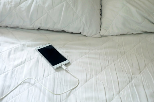 Smart Phone Is Charging On The White Bed