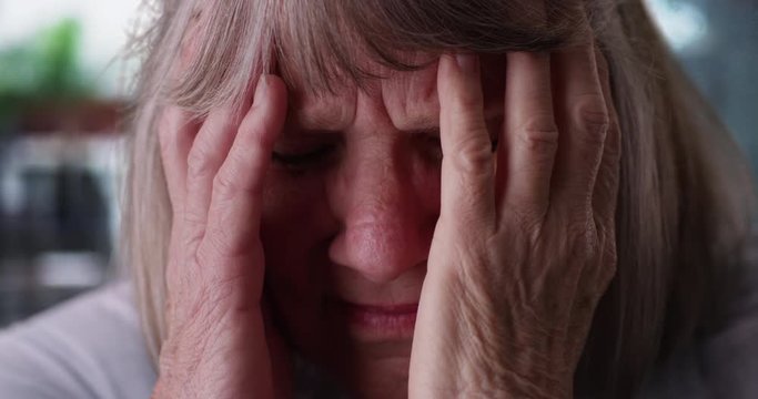 Close-up of stressed senior woman's face expressing pain in rainy setting, Tight shot of elderly Caucasian woman with migraine headache on rainy day, 4k 