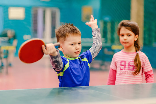 little boy standing in the tennis hall, spreading his hands to the sides. tennis hall, tennis racket, table tennis