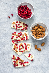 Cococnut oil white chocolate pomegranate nuts bark on concrete background. Top view, copy space.