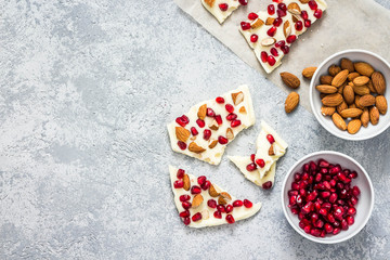 Gluten free white chocolate pomegranate nuts bark on concrete background. Top view, copy space.