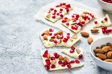 Salted white chocolate pomegranate nuts bark on concrete background. Selective focus, space for text. 