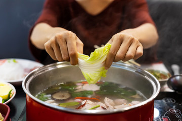 Young woman enjoy eating sukiyaki in hot pot at restaurant