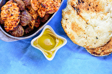 Meat kebab and Chicken fillet with spices served with hot pita or laffa or pitta bread and delicious hummus with fresh olive oil, close up. Top view.Traditional barbecue on Israeli independence day.