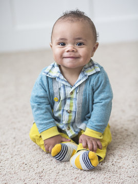 Beautiful smiling diverse baby boy portrait. Full length photo of an adorable child sitting indoors