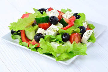 Greek salad on a white wooden background. Space for text or design.