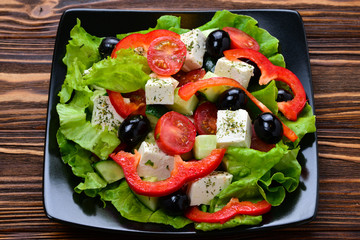 Greek salad on a wooden background. Space for text or design.
