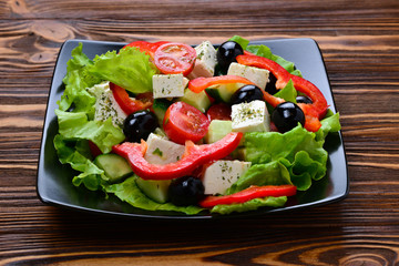 Greek salad on a wooden background. Space for text or design.