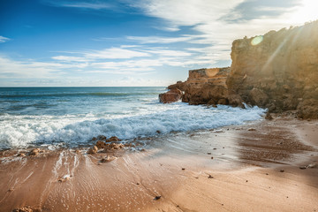 Beautiful coast of the ocean, Algarve, Portugal. Waves break against the rocks in the sun