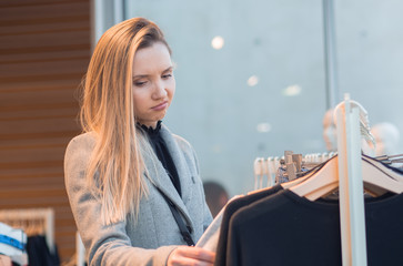 Irritaded female choosing clothes in retail store