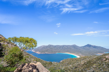 Wonderful view to stunning sandy beach blue turqouise water on warm sunny day with blue sky relaxing after hiking on top Mount Amos, Wineglass, Freycinet National Park, Coles Bay, Tasmania, Australia
