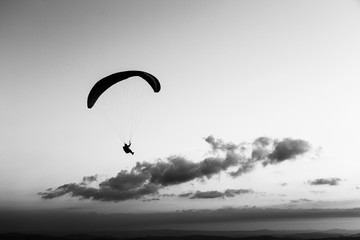 Beautiful shot of a paraglider silhouette flying over Monte Cucco (Umbria, Italy), with sunset on the background