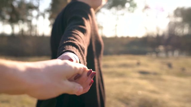 Follow me - happy young woman pulling guy's hand. Hand in hand walking to the bank of the river
