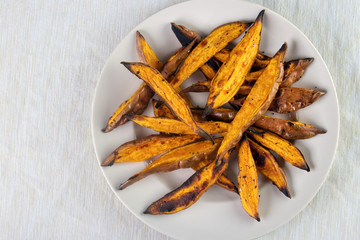 Oven roasted sweet potato wedges on plate , top view