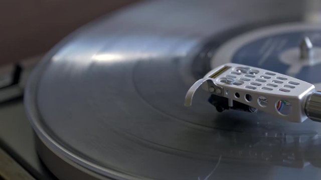Panning shot of turntable tone arm as music plays