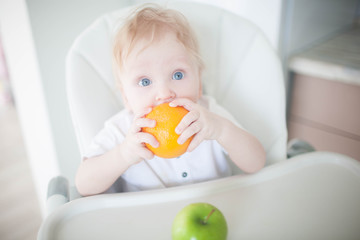 A baby boy in the kitchen eats fruit