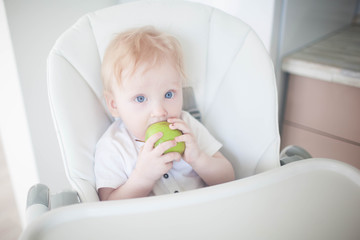 A baby breast eats a green apple