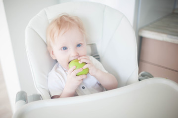 A baby breast eats a green apple