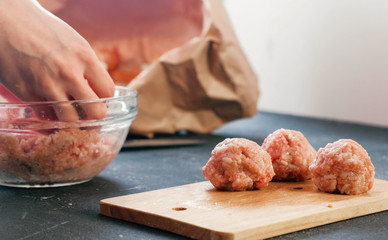 Close-up of a woman's hands making meatballs of minced meat with rice and put it on a wooden board.